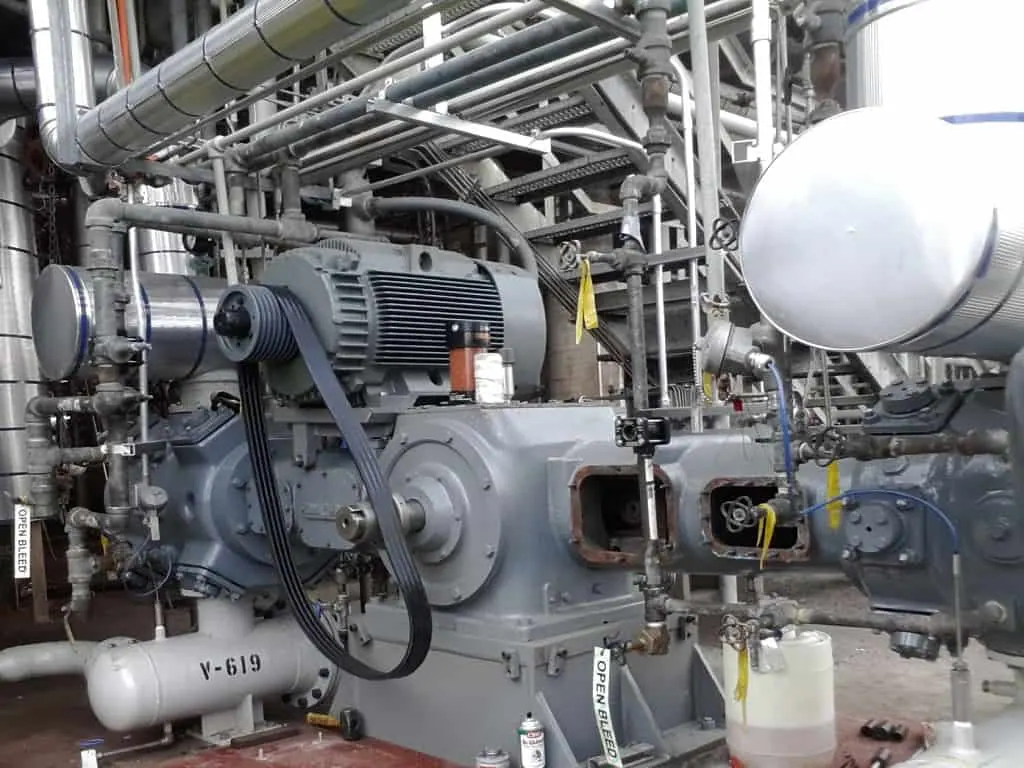 Compressor industrial e tubulação em sala de máquinas durante manutenção